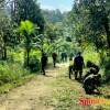 Anggota Satgas bersama dengan masyarakat Desa Bukit Pamewa bergotong royong bersama membersihkan badan jalan